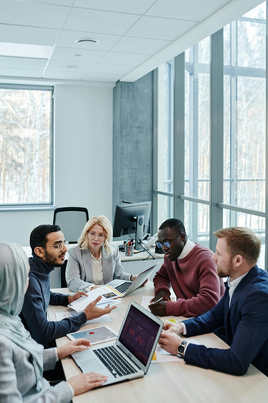 A diverse team of colleagues reviewing documents and data together in a bright conference room